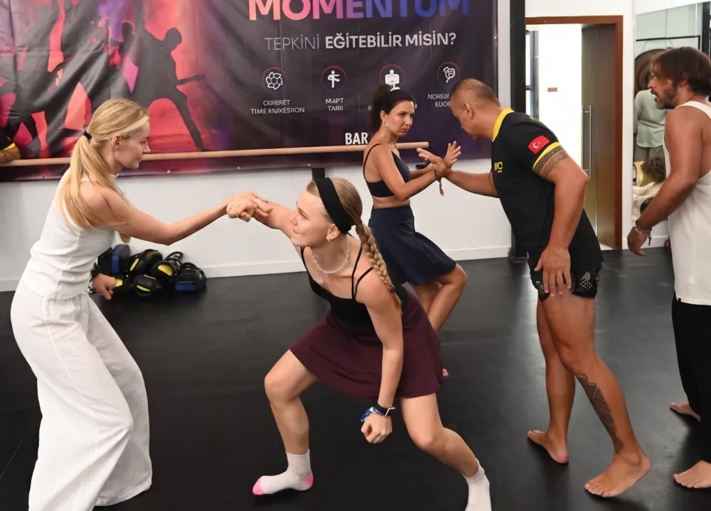 Momentum afişi önünde eşli çekme ve denge çalışması yapan katılımcılar