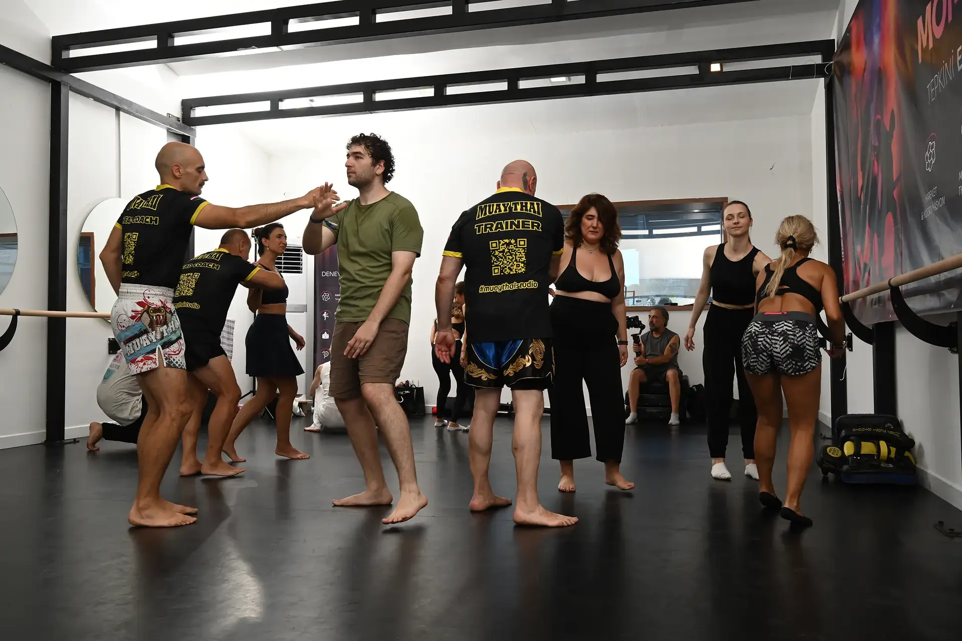 Stüdyonun genişinde eşler hâlinde muay thai çalışan katılımcılar